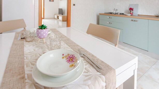 A dining table set with plates, cutlery, and a glass. There is a small potted plant on the table. - Casa Pandolfi, Apartment With Internal Parking and AC (Pescara)