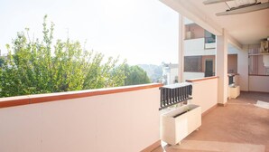 A balcony with a view of trees and buildings, a small kitchen area with a sink and cabinets, and a white radiator. - Casa Pandolfi, Apartment With Internal Parking and AC (Pescara)
