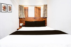 A bedroom with a wooden headboard, a black and white bedspread, and floral curtains. - Super Hotel O BKC Santacruz East (Mumbai)