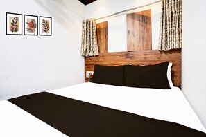 A bedroom with a wooden headboard, a bed with black and white bedding, and three framed leaf artworks on the wall. - Super Hotel O BKC Santacruz East (Mumbai)