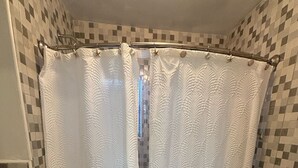 A bathroom with a shower curtain, a toilet, and tiled walls.