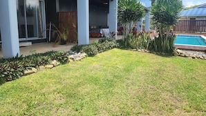 Ein modernes Haus mit überdachter Terrasse, Swimmingpool und gepflegtem Garten.