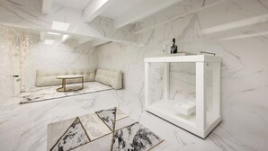 A modern interior with a marble floor, a white sofa, a glass display cabinet, and a skylight.