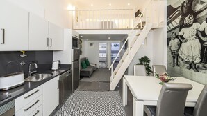 A modern kitchen with white cabinets, a stainless steel sink, and a dining area with a white table and chairs.