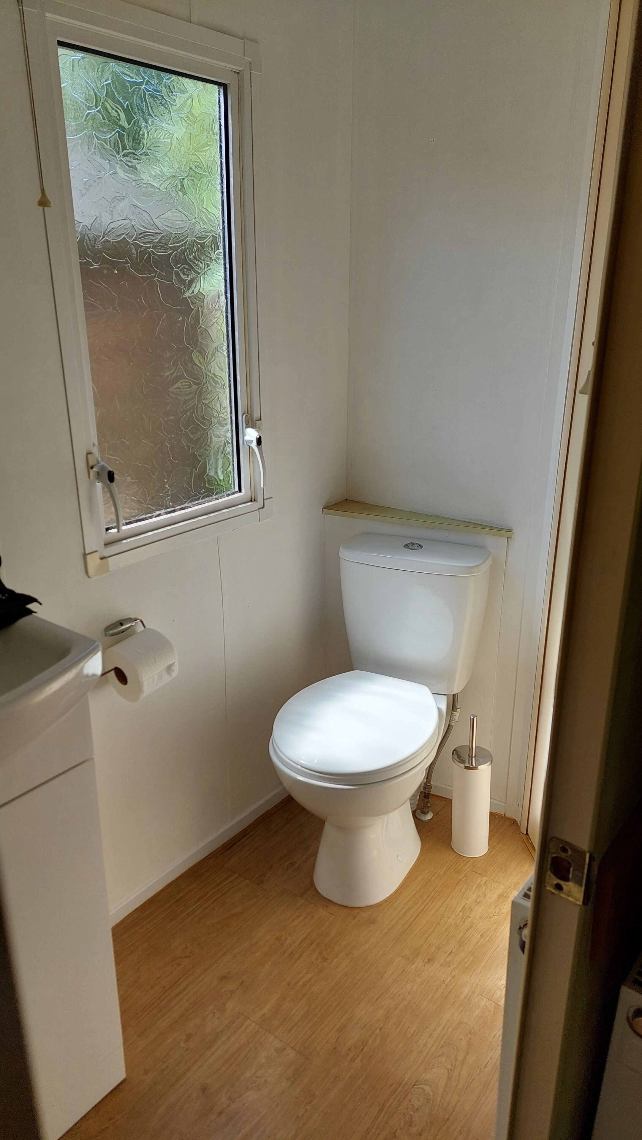 A small, clean bathroom with a toilet, a sink, and a window.