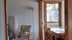 A wooden-floored room with a dining table and chairs, a lamp, and a window with a view of trees. - Nice, comfortable vacation home 4 beds, with terrace, near the lake (Stockholms län)