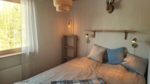 A bedroom with a bed, a window with curtains, a wall-mounted shelf with lights, and a mounted animal head. - Nice, comfortable vacation home 4 beds, with terrace, near the lake (Stockholms län)