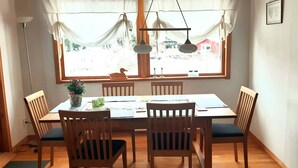 A dining area with a wooden table and chairs, a potted plant, and a window with curtains. - Nice, comfortable vacation home 4 beds, with terrace, near the lake (Stockholms län)