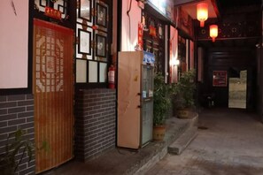A narrow alleyway with a traditional building, a wooden door, and a refrigerator outside. - Ju Yuan Ge Inn (Pingyao Ancient City North Gate) (Pingyao County)
