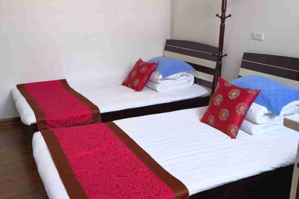 Two twin beds with red and blue pillows, a wooden headboard, and a red and brown bed runner.