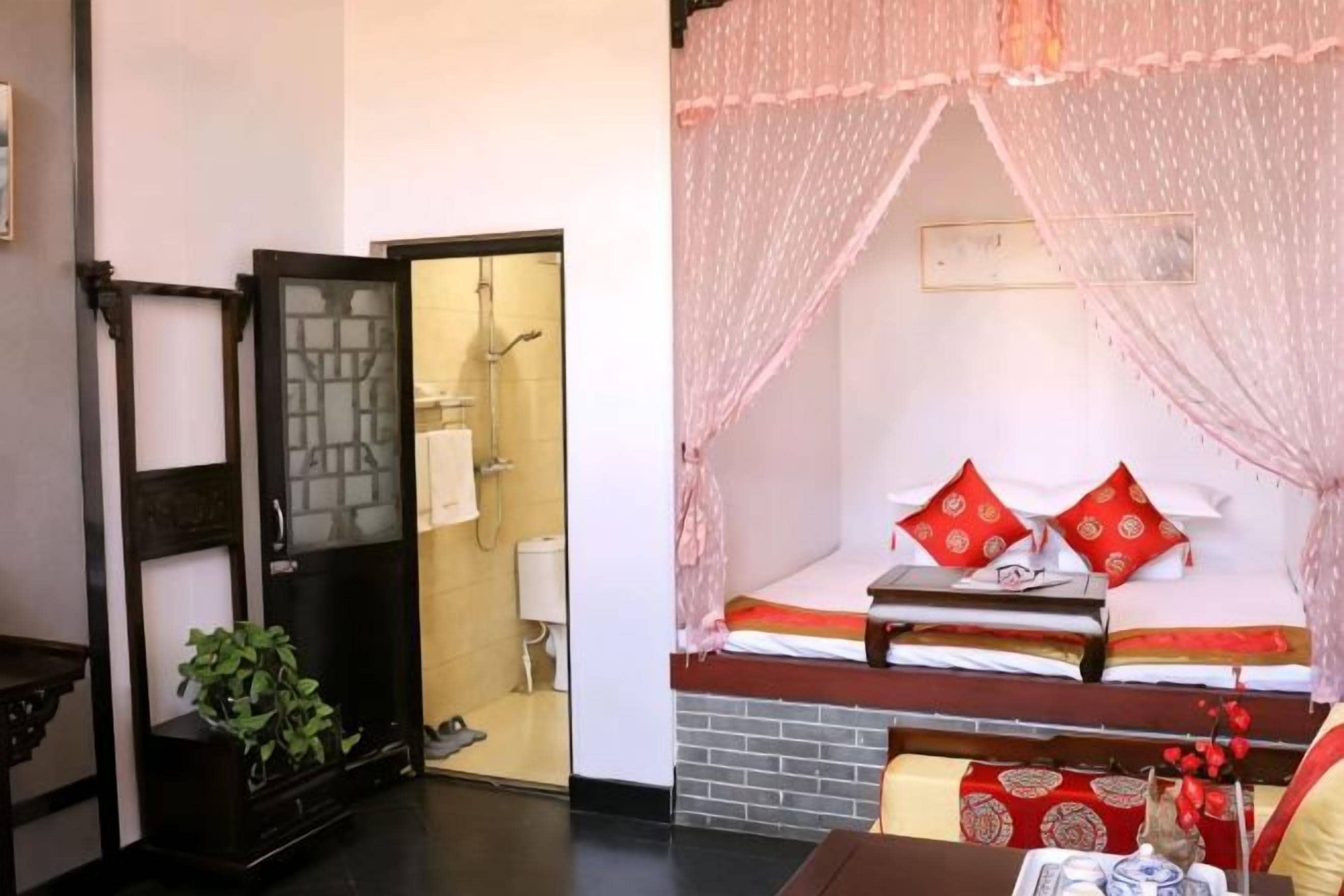 A room with a bed, a window, and a door leading to a bathroom.