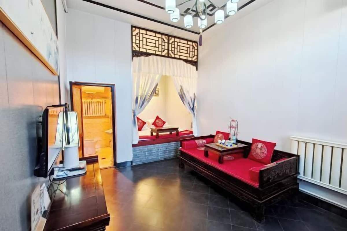 A room with a red sofa, a wooden coffee table, a TV, and a decorative screen.