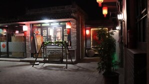 A traditional building with a tiled entrance, a small outdoor seating area, and red lanterns. - Ju Yuan Ge Inn (Pingyao Ancient City North Gate) (Pingyao County)