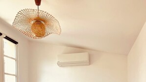 Une chambre à coucher comprenant un lit, des lampes de chevet, un luminaire suspendu et un appareil de climatisation.