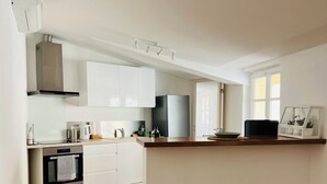 Une cuisine moderne avec des meubles blancs, un réfrigérateur noir et un plan de travail en bois.