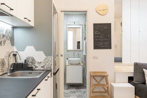 Bathroom features a large sink, matching faucet, and a mirror above, with a geometric tile pattern on the walls.