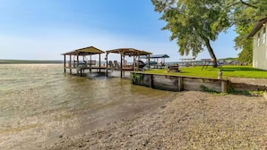 A lakeside property with wooden docks, a grassy area, and a house.