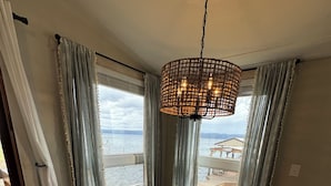 A dining area with a wooden bench, a woven table runner, and a hanging light fixture.