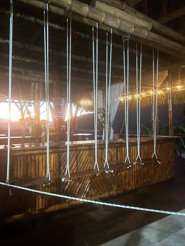 A wooden bar area with hanging ropes, bamboo ceiling, and a sign indicating a private area. - Renaco Glamping (Sauce)