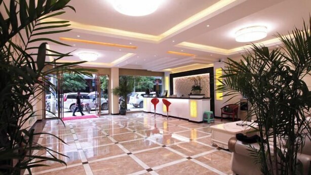 Vestíbulo de hotel con mostrador de recepción, zona de estar y suelo de mármol pulido.