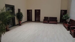 Una habitación amplia con piso de madera clara, dos bancos de madera y dos puertas.