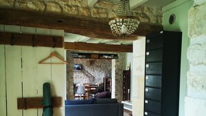 A rustic interior with a wooden floor, stone walls, a hanging light fixture, a sofa, and a fireplace.