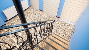 A staircase with patterned floor tiles, a metal railing, and blue walls. - Ilyada Hotel (Istanbul)