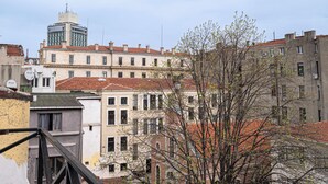 A multi-story building with a red-tiled roof, a prominent tower, and a tree in the foreground. - Ilyada Hotel (Istanbul)