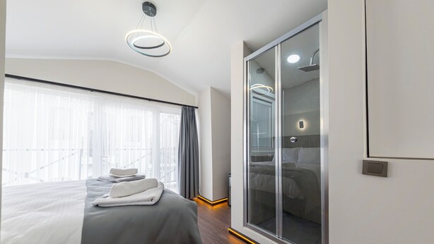 A modern hotel room with a large bed, a walk-in closet, and a large window with curtains. - Ilyada Hotel (Istanbul)