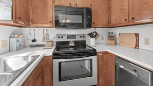 A kitchen with wooden cabinets, a stainless steel sink, a microwave, a stove, and a dishwasher.