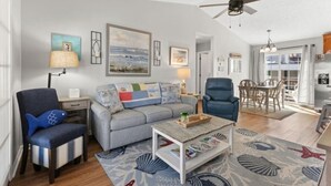 A living room with a sofa, armchairs, a coffee table, and a ceiling fan.