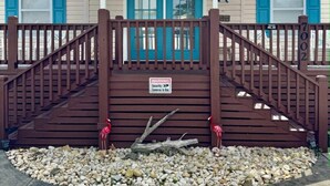 A building with a porch, a security warning sign, and a number sign.