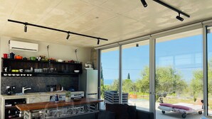 A modern kitchen with a large window, a sofa, and a cart. - Magia 22- Place for the Soul (Kathikas)