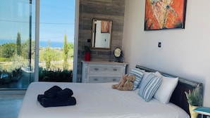 A bedroom with a large bed, a view of the outdoors, a wooden wall, and a painting. - Magia 22- Place for the Soul (Kathikas)