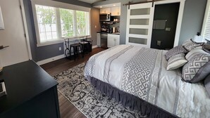 Un dormitorio con una cama grande, un escritorio y una kitchenette.