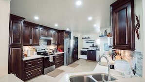A modern kitchen with dark wooden cabinets, stainless steel appliances, and a double sink. - Ocean front luxury villa iin gated golf course community with private beach. (Lowlands)