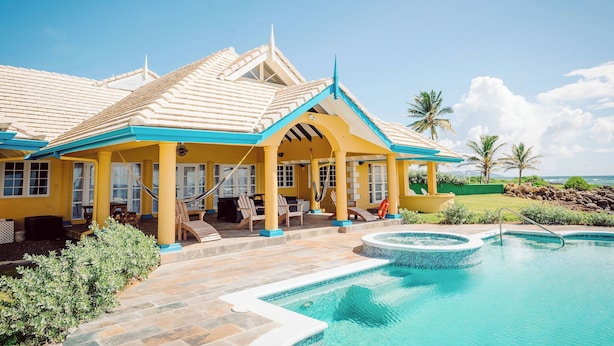 A resort with a pool, outdoor seating, and a view of the ocean. - Ocean front luxury villa iin gated golf course community with private beach. (Lowlands)