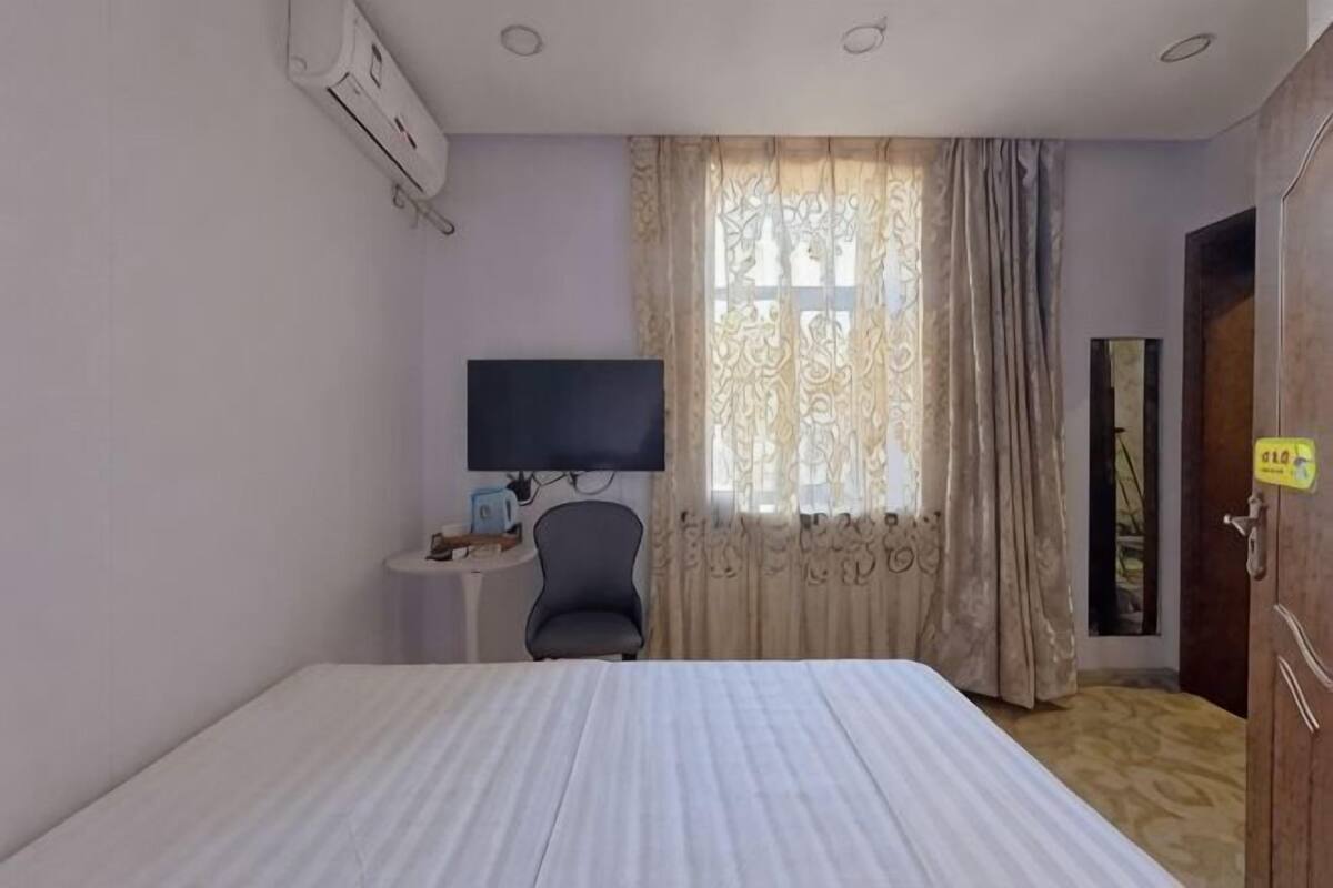 Ein Hotelzimmer mit einem Bett, einem Fernseher, einem Sessel und Vorhängen.