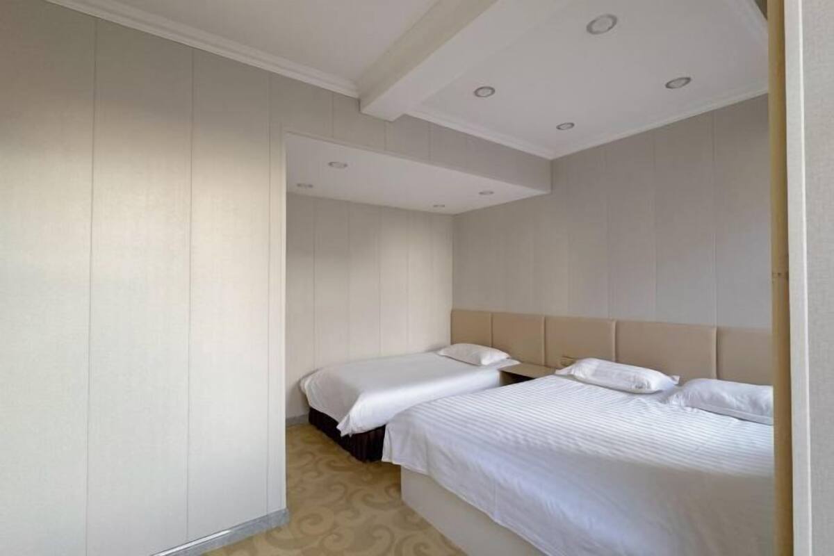 Ein Hotelzimmer mit zwei Betten, einem Kleiderschrank und einer Decke mit Einbauleuchten.