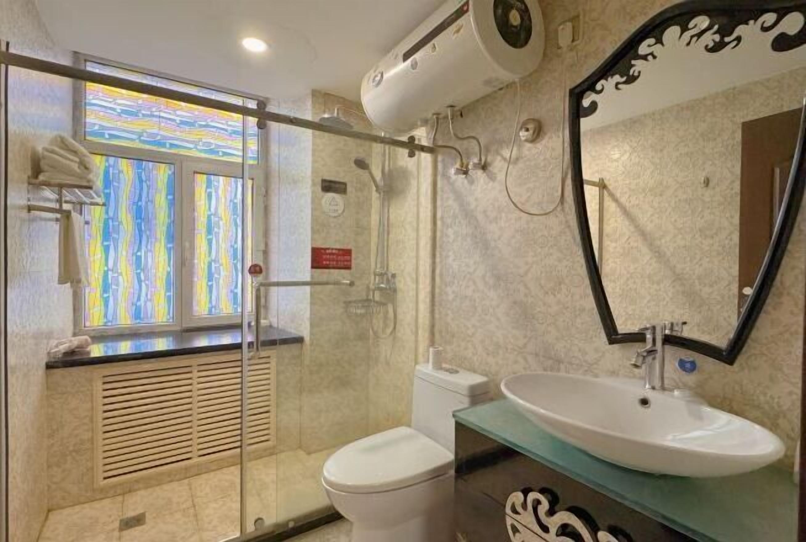 Ein Badezimmer mit Duschkabine aus Glas, Toilette, Waschbecken und Spiegel.