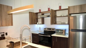 Una cocina moderna con armarios de madera, un refrigerador de acero inoxidable, un horno empotrado, un tostador y un lavamanos con grifo.
