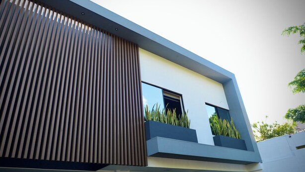 Un edificio moderno con techo inclinado, ventanas grandes y listones verticales de madera.