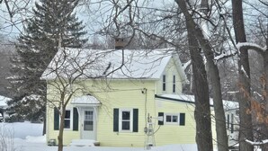 A yellow house with a front porch and a garage, surrounded by snow-covered trees. - 2-bedroom country house in West Springfield, PA with WiFi, AC (West Springfield)