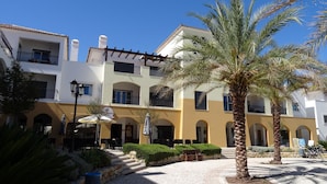 A multi-story hotel with balconies, outdoor seating, and palm trees. - The Pomar 2 Bedroom Suite -5 People Terrace Swimming Pools (Tavira)