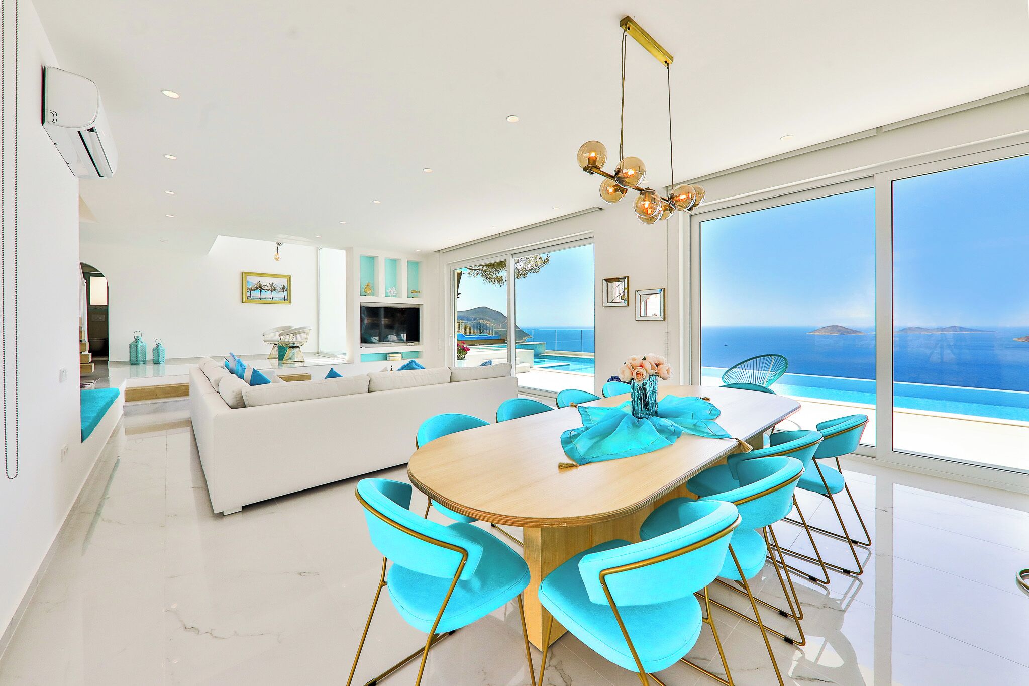 Een moderne woonkamer met een grote bank, een eettafel met stoelen en uitzicht op zee.