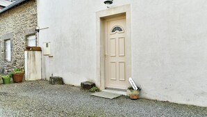 Een gebouw met een beigekleurige deur, een klein portaal en een stenen muur.