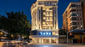 A multi-story hotel with a prominent sign, a curved facade, and a flat roof. - Feihong Boutique Hotel (Guangzhou North Railway Station) (Guangzhou)