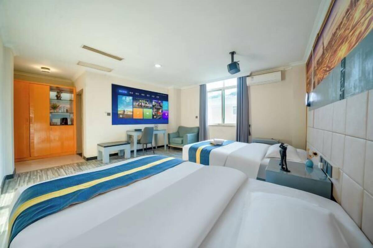 Habitación de hotel con dos camas, un escritorio, un televisor y una ventana.