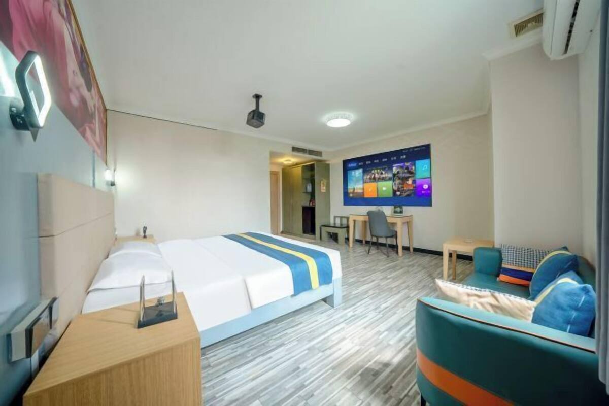 Una habitación de hotel con cama, escritorio, silla, televisor y sofá.