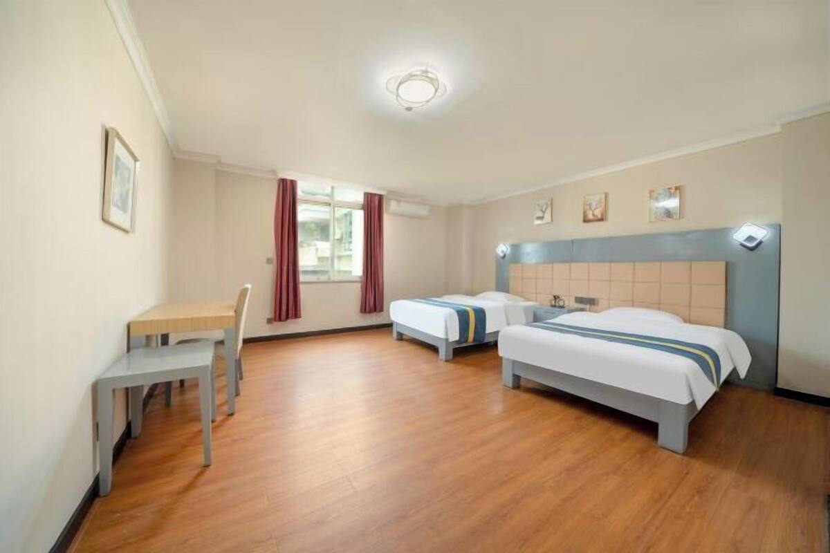 Habitación de hotel con dos camas individuales, un escritorio y una silla.